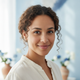 Portrait of a smiling woman with diverse features, looking directly at the camera with a gentle expression.